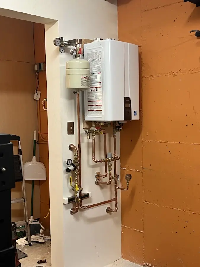 Plumbing technician inspecting water heater connections in Manitowoc